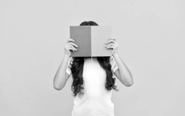 Öğrenmeye hazır liseli bir kız. Kitap ve eğitimin arkasına saklanıyor.