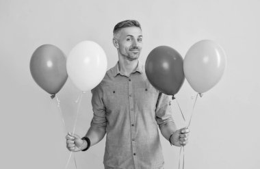 Gülümseyen yakışıklı adam sarı arka planda balonlar tutuyor, tatil