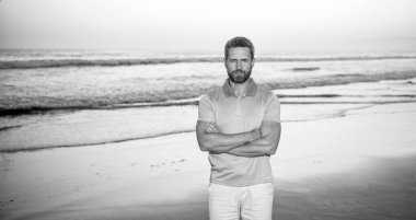 Sabah kumsalındaki traşsız adam. Gündoğumu plajındaki beyaz adam. Gömlekli sakallı adam..