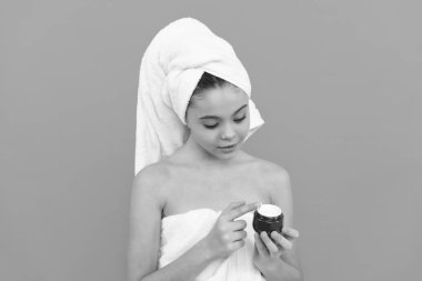 Banyo kulesindeki çocuk cilt kremi sürüyor, maske takıyor.