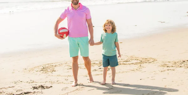 Ojciec i syn chodzą z piłką po plaży. tatuś z małym chłopcem w letni dzień. — Zdjęcie stockowe