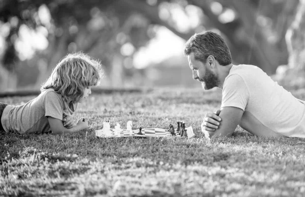 Familia feliz de papá e hijo niño jugando ajedrez sobre hierba verde en el parque al aire libre, familia —  Fotos de Stock