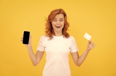 Heyecanlı genç bayan cep telefonu kartı kullanarak sarı arka planı izole etti..