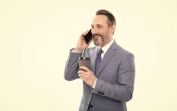 Cheerful mature man in suit talking on phone and drink coffee isolated on white, conversation — Stock Photo, Image