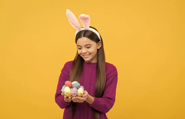 Kolory zjadacza. Króliczek trzyma malowane jajka. Wesołych świąt. śmieszne dziecko w uszach — Zdjęcie stockowe