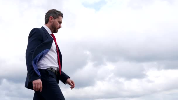 Réalisateur sérieux homme en costume formel vérifier montre tout en marchant dans le ciel nuageux, le temps — Video