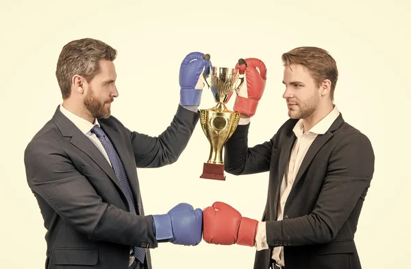 two business men in boxing gloves hold champion cup after corporate battle for leadership, victory.