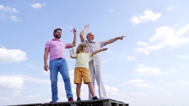 Сім'я хлопчика дитини з батьком і старим чоловіком вказують пальці, що тримають паперові площини неба високі, кидаючи — стокове відео
