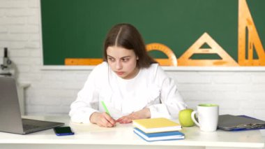 Ciddi bir okul çocuğu sınıfta defterine yazı yazar, sınavlar