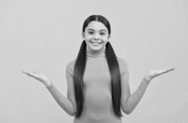 Mutlu genç kız ürün sunuyor. Fotokopi alanında. Sarı arka planda.