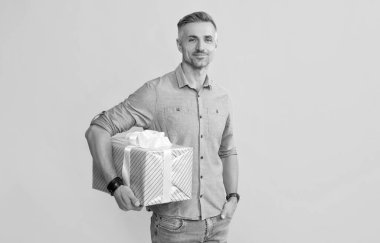 Gülümseyen adam hediye kutusunu sarı arka planda tut, alışveriş yap