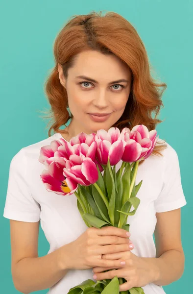 Mavi arka planda lale çiçeği buketi olan genç bir kadın. — Stok fotoğraf
