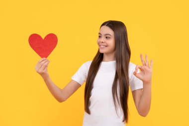 Kırmızı kalpli mutlu çocuk. Sarı arka planda jest yap, tatlım.