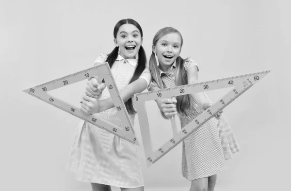 Niños en edad escolar feliz sostienen reglas triangulares fondo amarillo, geometría —  Fotos de Stock