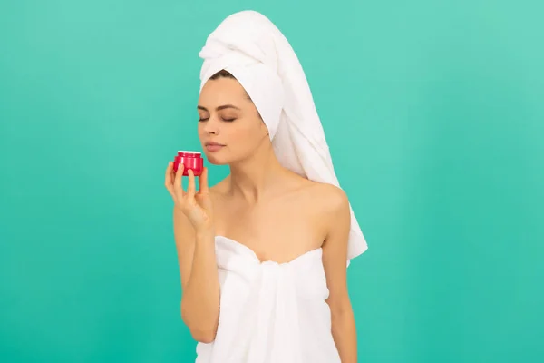 Bela mulher em toalha cheiro creme de pele no fundo azul — Fotografia de Stock