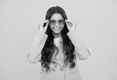 Şık mor ceketli, sarı arka planda güneş gözlüklü güzel mutlu çocuk, moda düşkünü..