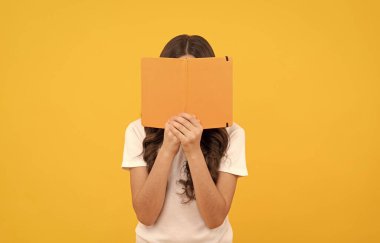 Okumaya hazır gülümseyen okul çocuğu kitap ve bilginin arkasına saklan.