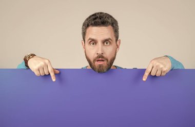 Şaşırmış sakallı adam boş mavi pankartı işaret ederek reklam ve dedikodu için fotokopi alanı verdi..