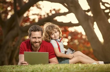 Mutlu baba ve oğul ailesi ders için dizüstü bilgisayar kullanıyor. Kulaklıklarda müzik, aile hafta sonu..