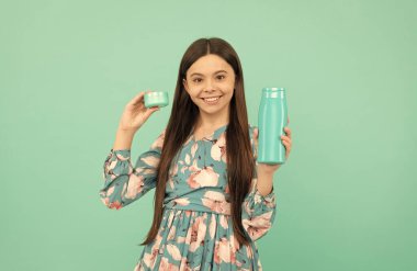 Duş jeli ve yüz kremi olan çocuk. Mutlu kız şampuanı tutar. Saç maskesi kremi olan çocuk