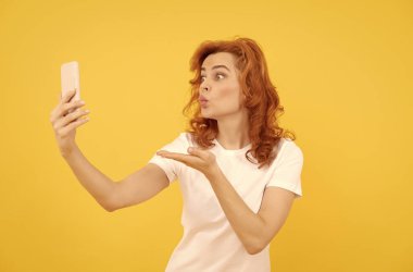 Kız kameraya el öpme hareketi yapıyor telefon sarısı arka plan, mobil cihaz