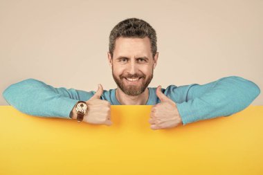 Boş kağıt pankartın arkasında mutlu bir adam anons için kopya alanı ile baş parmağını kaldır, yaratıcılığı göster.