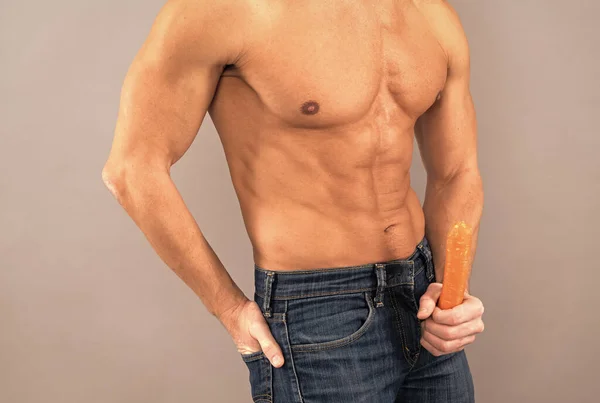 Healthy man with fit torso hold carrot as penis. Sexual potency. Sexual arousal. Erection. — Stock fotografie