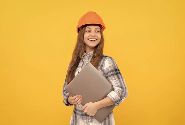 Menina adolescente no capacete usar laptop. Construtor miúdo espera computador. construção e construção. webinar. — Fotografia de Stock