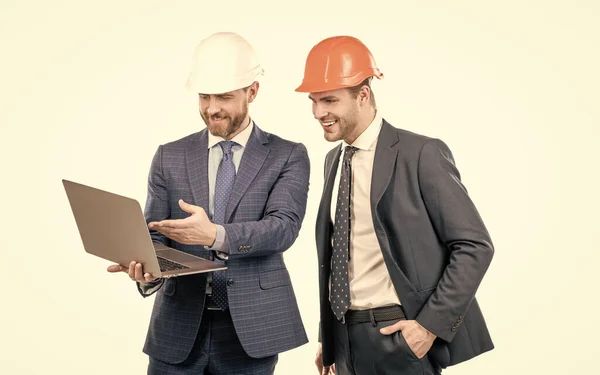 Två affärsmän män partner i kostym och skyddshjälm arbete på laptop på nätet, affärspartner. — Stockfoto