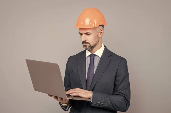 Uomo d'affari in casco edificio utilizzando il computer, conferenza online di sicurezza — Foto Stock