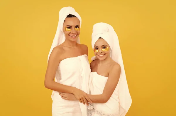 Moisturizing skin. cosmetology. mom and daughter in terry towel use patch. beauty day in family spa. — Fotografia de Stock
