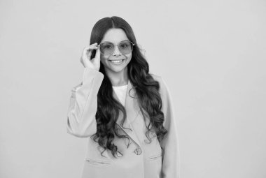 Güzel, kıvırcık saçlı, mor ceketli, sarı arka planda güneş gözlüklü, güzel bir çocuk..