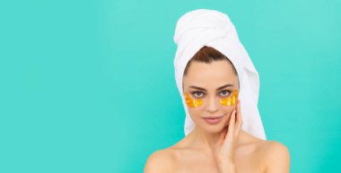 Genç kızın yüzünde havluyla kolajen altın göz bantları var. Boşluğu kopyala