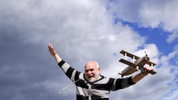 Gelukkige oude man gebruiken verbeelding om te doen alsof vliegen op houten vliegtuig in de lucht, stel je voor — Stockvideo