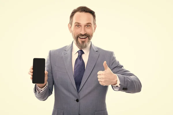 Glücklicher Geschäftsmann präsentiert Smartphone isoliert auf weißem Zeigen Daumen nach oben Kopierraum, Präsentation. — Stockfoto