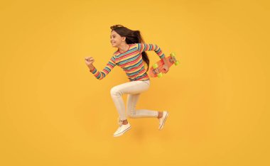 Mutlu enerjik genç kaykaycı kız. Pennyboard kaykayıyla atlıyor.