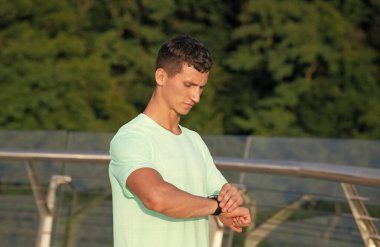 Atletik adam açık hava antrenmanı, spor zamanlaması sırasında bilek nöbetini kontrol ediyor.