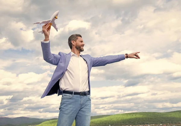Dojrzałe szczęśliwy człowiek przedsiębiorca w kurtka trzymać zabawki samolot na tle nieba, wolność — Zdjęcie stockowe