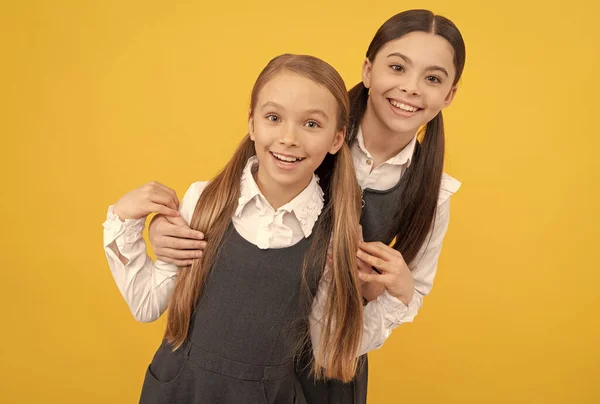 Niños de la escuela feliz con aspecto de belleza usan pelo largo en uniformes formales fondo amarillo, salón —  Fotos de Stock