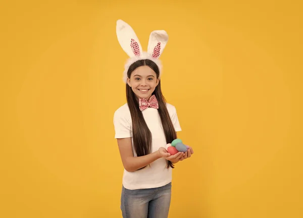 Feliz Páscoa criança menina em orelhas de coelho e laço segurar ovos pintados, caça ao ovo — Fotografia de Stock