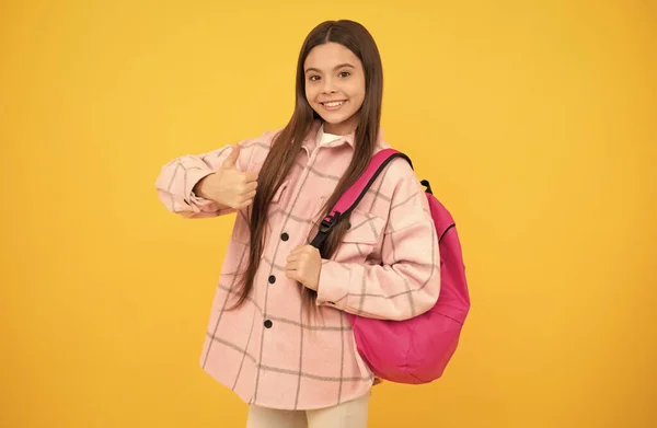 Menina feliz usar camisa xadrez rosa levar mochila escolar, polegar para cima — Fotografia de Stock
