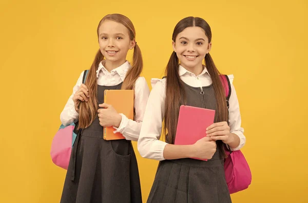 Niños felices en uniformes de fomal con libros de estudio llevan bolsas de la escuela fondo amarillo, conocimiento —  Fotos de Stock