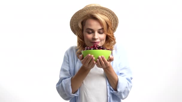 Dodatnia kobieta w słomkowym kapeluszu pachnąca świeżo dojrzałą jagodą wiśniową, wybiórcza ostrość, owoce sezonowe — Wideo stockowe