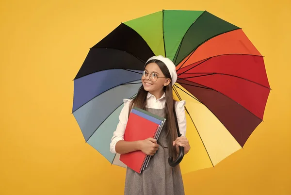 Torniamo a scuola. vivida protezione contro la pioggia. ragazza felice in bicchieri tenere quaderno. istruzione. — Foto Stock