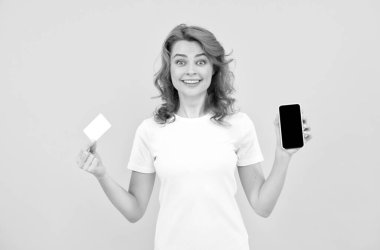 Heyecanlı genç bayan cep telefonu kartı kullanarak sarı arka planı izole etti..