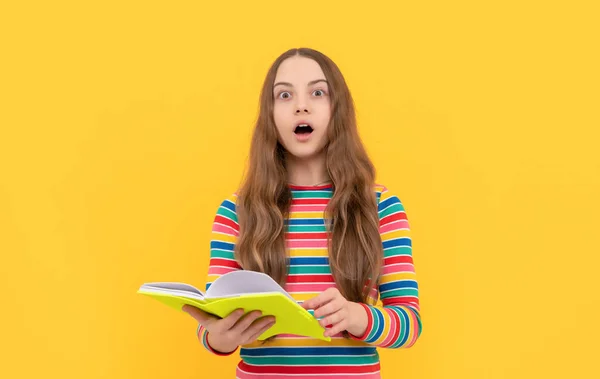 Удивительные открытые глаза ребенка держать школьную книгу желтый фон, сюрприз — стоковое фото