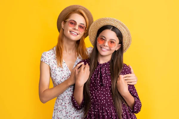 Felice madre e figlia in cappello di paglia su sfondo giallo — Foto Stock