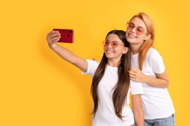 Anne ve çocuk blogcuları. Güzel kadın ve kız akıllı telefonla selfie çekiyorlar. Selfie ailesi.