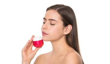 Genç kız yüz için krem kavanozu tutuyor beyaz arka planda izole edilmiş cilt, kozmetik