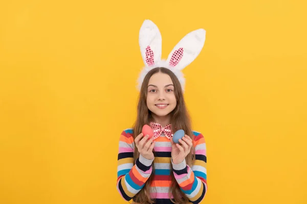 Alegre adolescente niño en conejito orejas y pajarita celebrar Pascua huevos en amarillo fondo —  Fotos de Stock